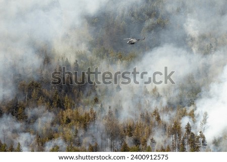 Rescue helicopter flying over a mountainside forest fire near Sparwood, British Columbia, Canada during the 2023 wildfire season Royalty-Free Stock Photo #2400912575