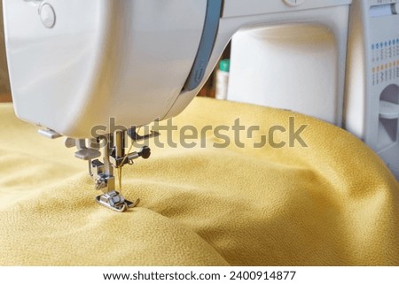 Modern sewing machine with yellow velours fabric. Special presser foot and zipper close up. Sewing process clothes, curtains upholstery. Business, hobby, handmade, zero waste, repair concept