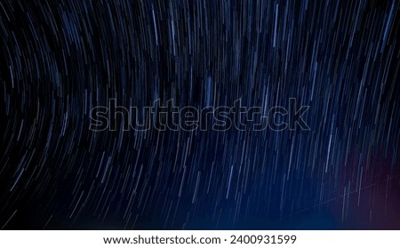 Abstract photo of Blue Night sky star trail background.Startrails on a dark blue sky at night,center sky area.Rotating star lines