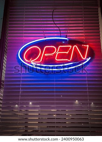 Neon open signage on a restaurant store front window at night with blinds behind. Located on Rideau Street Ottawa Ontario Canada