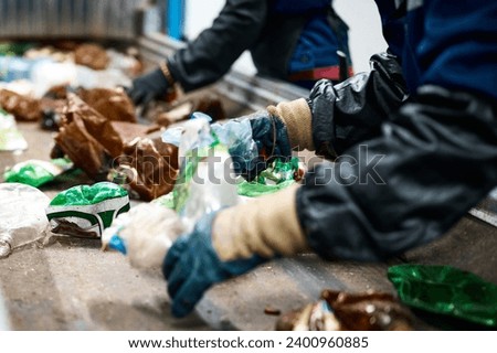 Worker sorts trash on conveyor belt at waste recycling plant Royalty-Free Stock Photo #2400960885