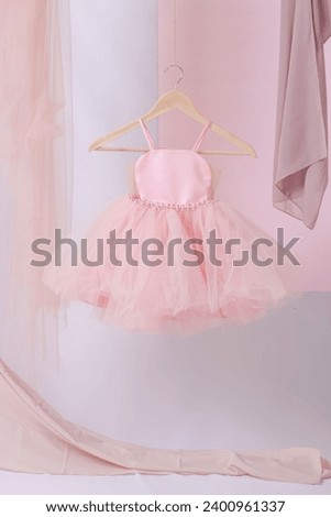 Beautiful dressy lush pink and blue dresses for girls on hangers, Kids dresses with feathers for prom and holiday Royalty-Free Stock Photo #2400961337
