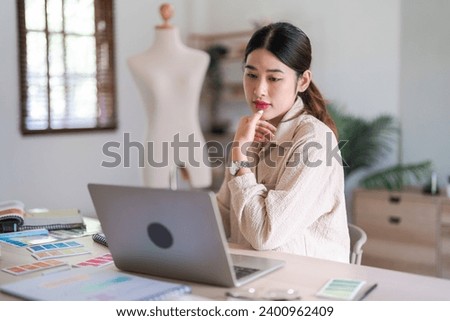 Fashion designer women read data on laptop to designing new dress collection and sketching in paper.