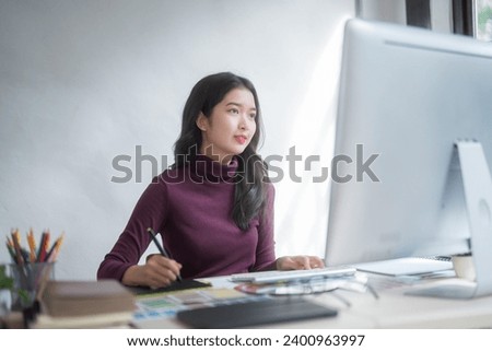 Graphic designer freelance women thinking creative ideas to sketching logo brand on digital tablet and typing on computer while working about graphic design with technology equipment in home studio.
