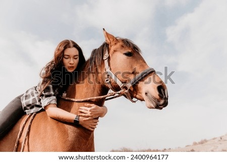 Young happy woman in hat with her horse in evening sunset light. Outdoor photography with fashion model girl. Lifestyle mood. Concept of outdoor riding, sports and recreation.