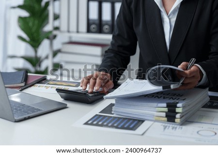 Asian businesswoman works on laptop and calculates with financial calculator from graphs, statistics, charts. Planning. Business success results in modern office.