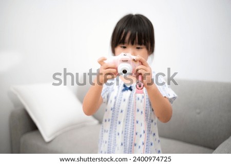 Girl Playing with Toy Camera in Home Room