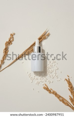 Glass bottle with dropper arranged over white background with rice and wheat ears. Mockup design. Rice water is known to help reduce skin irritation