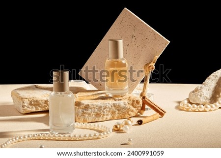 Creative background for advertising perfume product. Two glass bottles displayed with cinnamon stick, pearl necklace, stone and brick on black background. Mockup for design