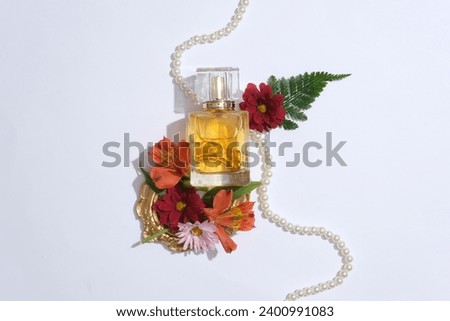 Simple but elegant concept for a perfume of women advertisement. A glass bottle unlabeled with beautiful flowers, fern leaf and pearl necklace decorated on white background