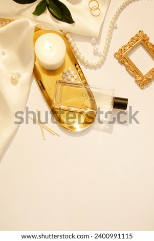 Flat lay, top view trendy lifestyle blog with decorative pearl jewelry on white background with candles and silk fabric. Mockup for unlabeled perfume bottle displayed for advertising. Copy space