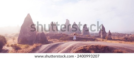  Woman in white dress walking in fairy rock formation landscape of Cappadocia, Turkey, Goreme national park
