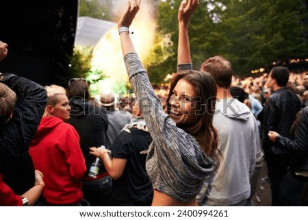 Happy woman, portrait and crowd in music festival for party, event or DJ concert in nature. Excited female person smile with hands up and audience at carnival, performance or summer fest outside Royalty-Free Stock Photo #2400994261