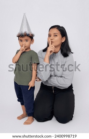 Full body smiling happy mother and kid boy asian wearing casual clothes and silver cone hat showing silent gesture isolated on white background Royalty-Free Stock Photo #2400998719