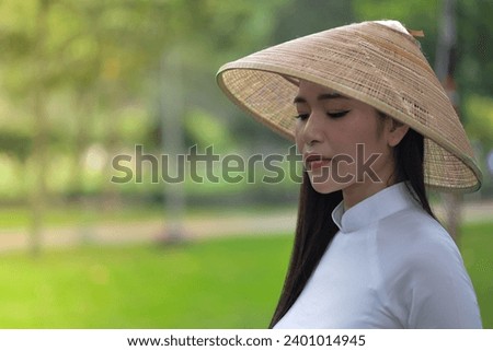 Royalty high quality free stock photo young gorgeous girl wearing a white traditional costume of Vietnam with conical hat and holding a basket full of daisies