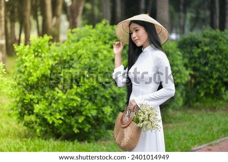 Royalty high quality free stock photo young gorgeous girl wearing a white traditional costume of Vietnam with conical hat and holding a basket full of daisies