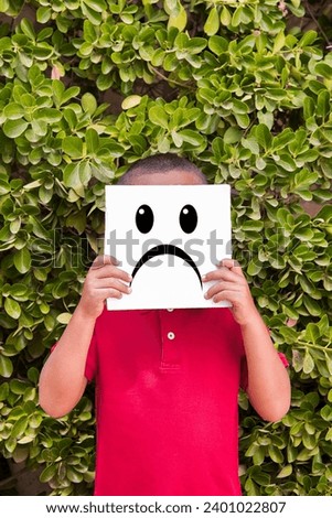 Boy with sad emoticon on a plant background 
