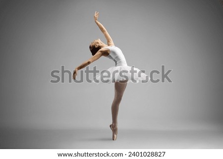 Full length shot of a ballerina dancing and leaning backwards isolated on gray background Royalty-Free Stock Photo #2401028827
