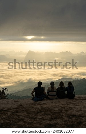 A group of people taking a photo of mountain view point colved with sea of cloud in the morning with beautiful sky (Phu Kradueng, Thailand)