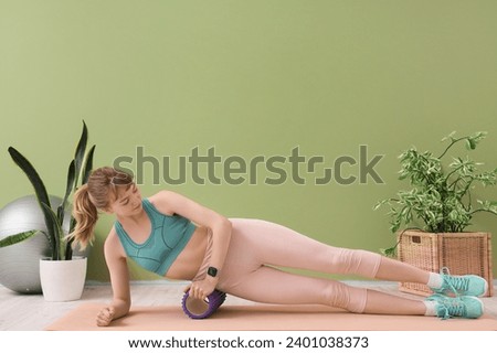 Young sporty woman training with foam roller at home