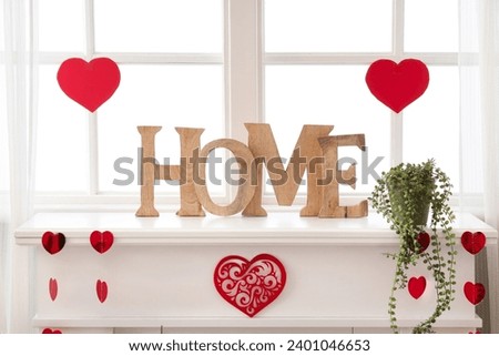 Mantelpiece with decorative word HOME and hearts for Valentine's Day celebration near window Royalty-Free Stock Photo #2401046653