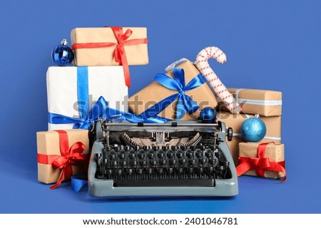 Vintage typewriter with Christmas gifts on blue background