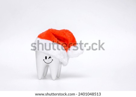 smiling healthy tooth in a Santa Claus or Father Frost hat on a white background. Christmas or New Year gift for dentist