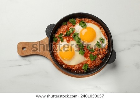 Delicious shakshuka in frying pan on white marble table, top view Royalty-Free Stock Photo #2401050057