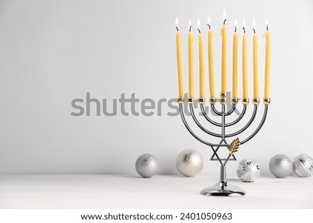 Hanukkah celebration. Menorah with burning candles and holiday ornaments on white wooden table, space for text