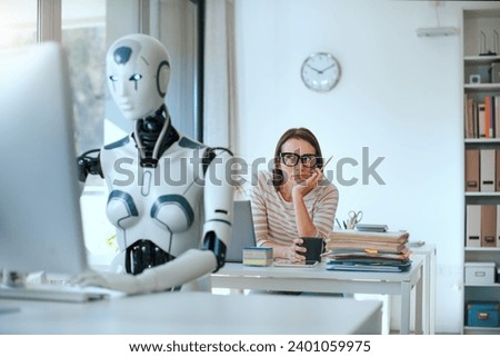 Disappointed stressed woman and AI robot sitting at the office desk and working Royalty-Free Stock Photo #2401059975