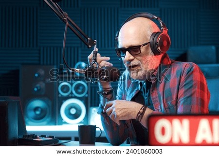 Professional radio host wearing headphones and talking into the microphone: radio and communications concept