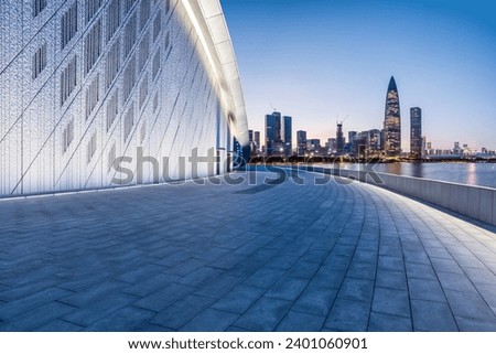 Empty square floor and brick wall buildings with city skyline in Shenzhen at night, China. Royalty-Free Stock Photo #2401060901