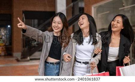 Group of attractive, fun Asian girls in trendy clothes are enjoying shopping in the city, walking with their shopping bags, spending a holiday weekend together. Fashion and lifestyle concepts