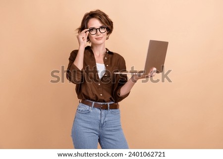 Photo of cheerful smart lady wear brown shirt spectacles texting emails modern device isolated beige color background