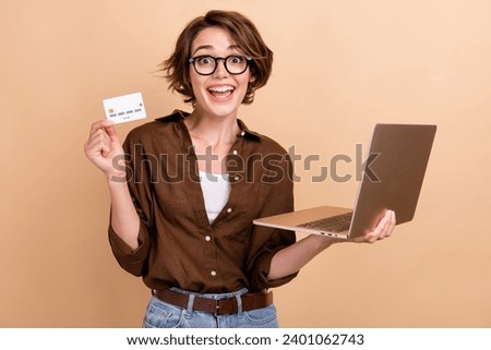 Photo of excited funky lady wear brown shirt spectacles online shopping modern device isolated beige color background