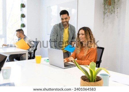 Dynamic collaboration unfolds as two cheerful office professionals work together at a computer, sharing ideas and fostering a positive work environment in a modern office setting Royalty-Free Stock Photo #2401064583