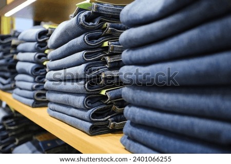 Many jeans in closet. Stack of jeans on shelf. Concept of buy , sell , shopping and jeans fashion .