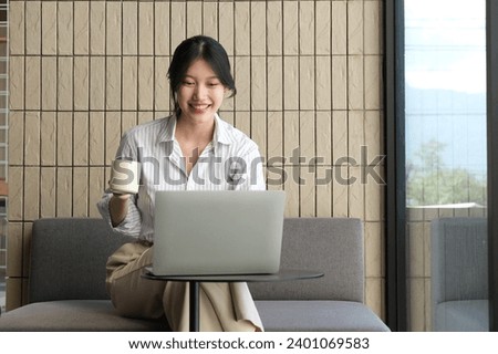 A beautiful girl with a smile on her face communicates with colleagues online, on a laptop.
