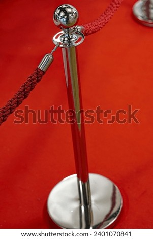 Close-up of barrier with metal pole with globe on top with red rope and red carpet in the background inside of department store. Photo taken December 13th, 2023, Zurich, Switzerland.