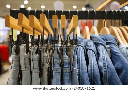 Jeans on the hanger in the store. Clothes on hangers in shop for sale. Blur background. Fashionable clothes in a boutique. Various clothing on market. Shopping in store.