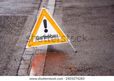 Gardeners doing maintenance at garden at Swiss City of Zürich with mobile warning sign at pavement on a cloudy autumn day. Photo taken December 13th, 2023, Zurich, Switzerland.