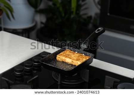 Chef man hands cooking Tamagoyaki or Tamago traditional Japanese Rolled Omelette recipe, made by rolling several layers of cooked scrambled whisking eggs in pan into a rectangular omelet. Royalty-Free Stock Photo #2401074613