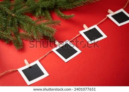 Layout of square photos on a red background. Christmas tree branches on the side of the frame. Concept of New Year holidays.