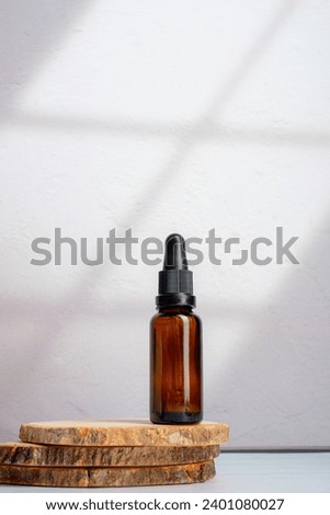 Cosmetic bottles made of dark amber glass on wooden plate on white background,with palm leaves shadow.