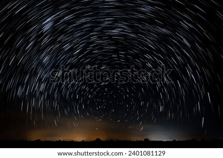Abstract photo of Blue Night sky star trail background.Startrails on a dark blue sky at night,center sky area.Rotating star lines. The North Star and meteor showers. Royalty-Free Stock Photo #2401081129