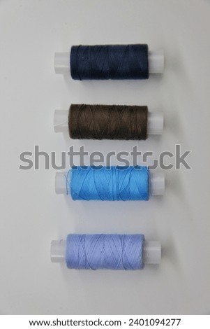 threads of different colors in spools on a white background isolated. blue yellow green dark and light shades sewing thread. 