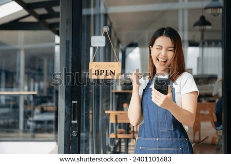 Young female hanging a welcome sign in front of a coffee shop. Beautiful waitress or hostess holding a tablet preparing  in a restaurant.
