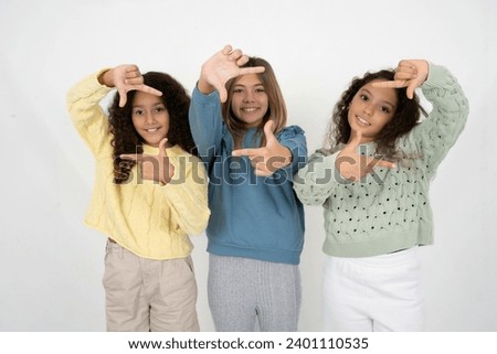 Three young multiracial kid girls making finger frame with hands. Creativity and photography concept.