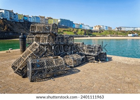 Empty Lobster Pots on Tenby Harbour Tenby South Wales with the colourful houses of Tenby in the background above the coast and beach Royalty-Free Stock Photo #2401111963