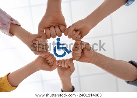 Inclusion concept. People holding fists together around international symbol of access together, bottom view